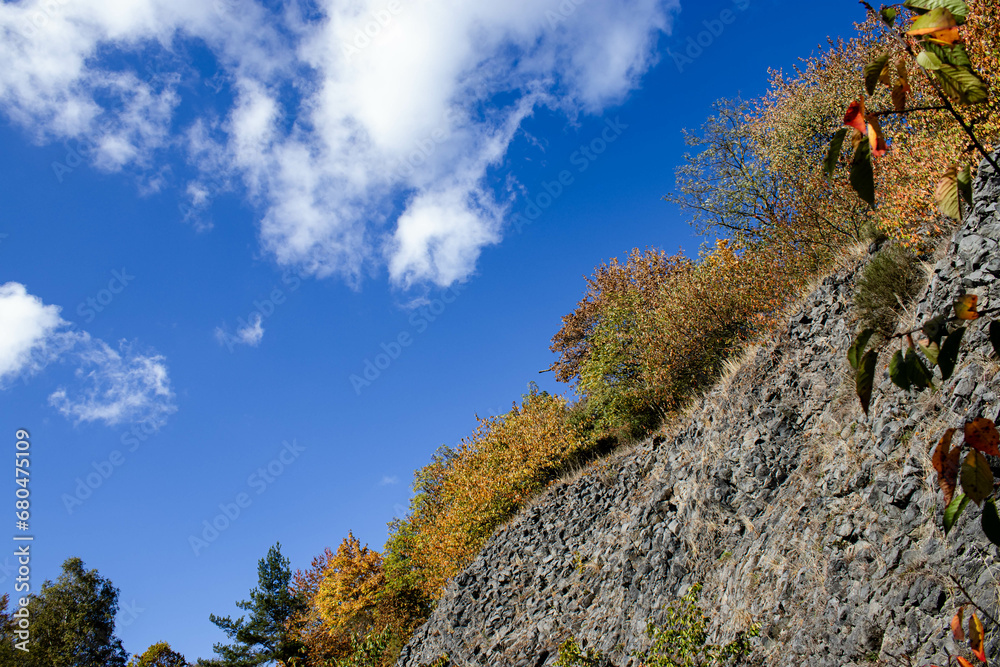 Autumn begins. Against the background of rocks and yellow trees, the sky with clouds looks fabulous. The colors are divided by lines, but everything is harmoniously distributed among themselves.