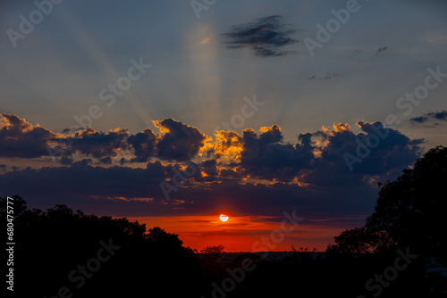 Orange sunrise on the horizon with emphasis on the sun's rays and birds in the distance. Idyllic Setting