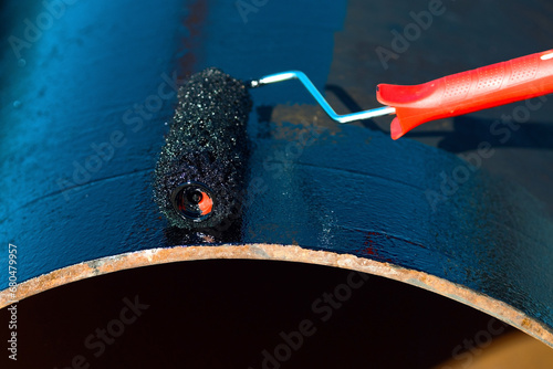 Bilde på lerret Metal pipe is painted with paint roller with black paint or bitumen