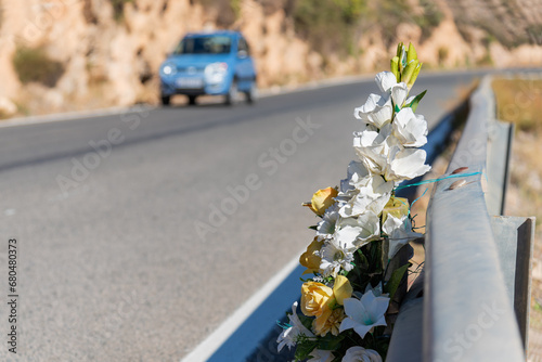 Bouquet of flowers tied to a road guardrail in memory of a person who died in an accident with a car driving nearby.