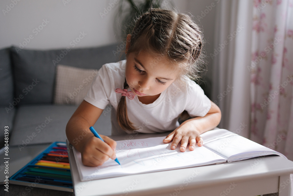Happy adorable little girl sitting at the table and smile. Beautiful five year old girl at home. Happy adorable little girl sitting at the table and smile. Beautiful five year old girl at home.