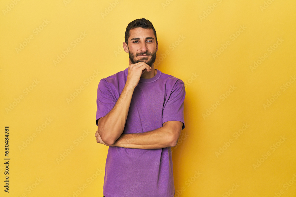 Young Hispanic man on yellow background smiling happy and confident, touching chin with hand. Young Hispanic man on yellow background smiling happy and confident, touching chin with hand.