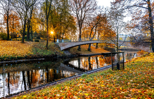 Pedestrian bridge over the river in old city park during autumn