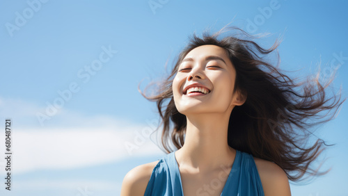 A Asian woman breathes calmly looking up isolated on clear blue sky © pariketan