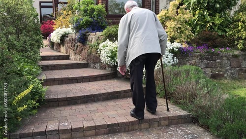 Senior man walks up steps with walking stick, England