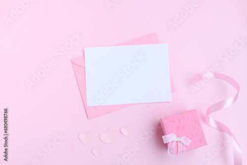 Pink envelope with white greeting card, Pink gift box and pink heart shape papercut on pink background, Love and Valentine concept © voranat