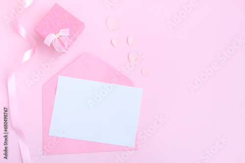 Pink envelope with white greeting card, Pink gift box and pink heart shape papercut on pink background, Love and Valentine concept © voranat