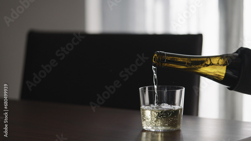 pour white wine into glass on walnut table