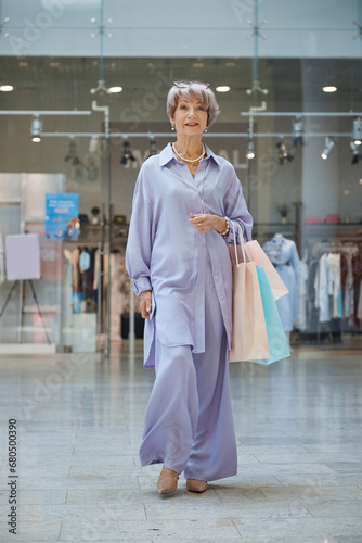 Full length portrait of senior woman with shopping bags over store showcase
