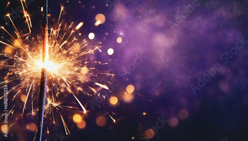 Sparkler burning bright with shiny sparks. Dark purple festive background. Happy New Year concept.