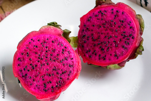 Red Dragon fruit slice and cut half on white plate.