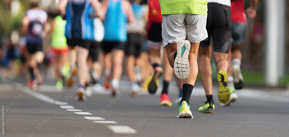 Marathon runners running on city road, large group of runners, close-up legs runners running sport marathon, male jogging race in asphalt road, athletics competition Marathon runners running on city road, large group of runners, close-up legs runners running sport marathon, male jogging race in asphalt road, athletics competition
