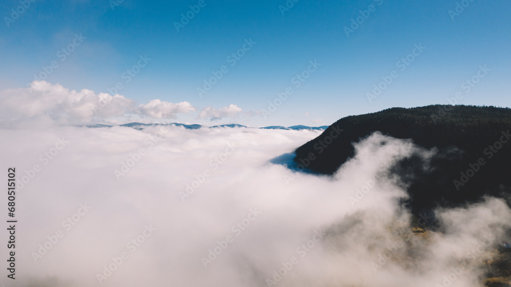 Flying above clouds, aerial view of distant mountain range above clouds
