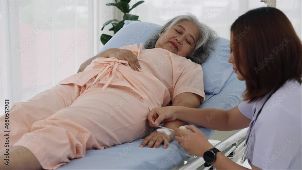 Female nurse takes care of inserting an iv line for an elderly asian