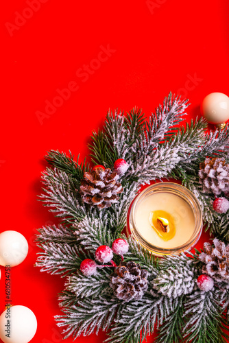 Beautiful christmas tree wreath with artificial snow and pine cones  white candle and white christmas toys from above on red background.