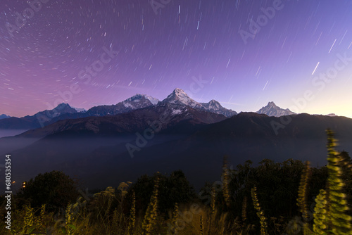 Machapucchare mountain peak and Annapurna range at dawn, under star trail night sky, from Poon Hill viewpoint, Himalayas, Nepal