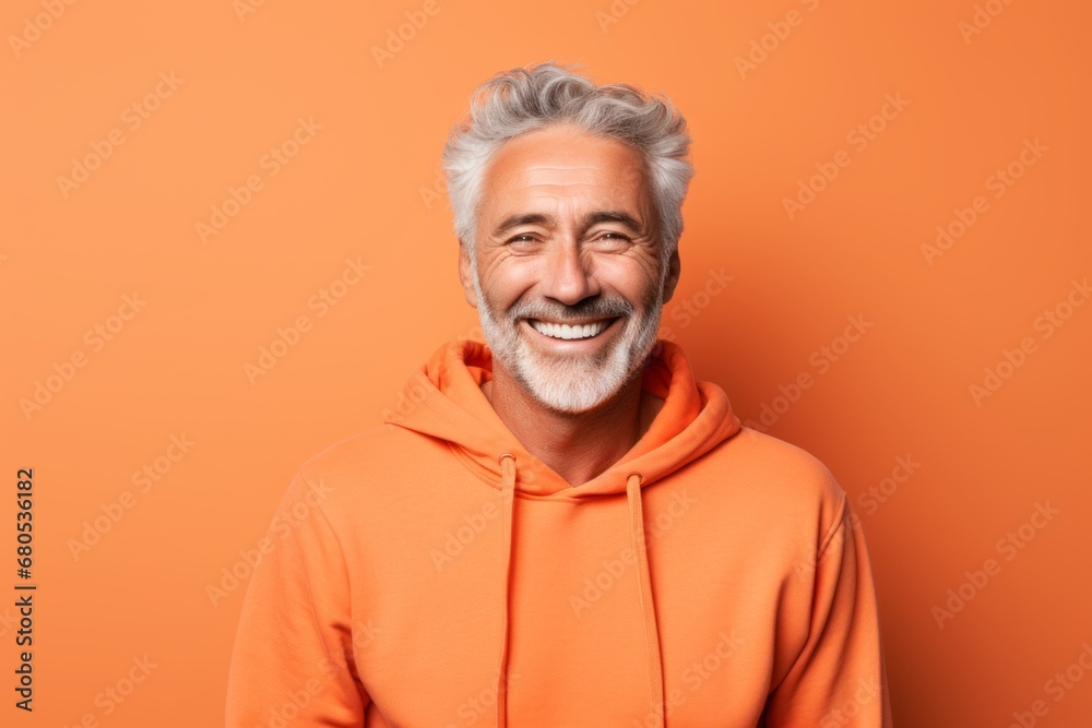Portrait of a happy man in his 60s sporting a comfortable hoodie against a pastel orange background. AI Generation Portrait of a happy man in his 60s sporting a comfortable hoodie against a pastel orange background. AI Generation
