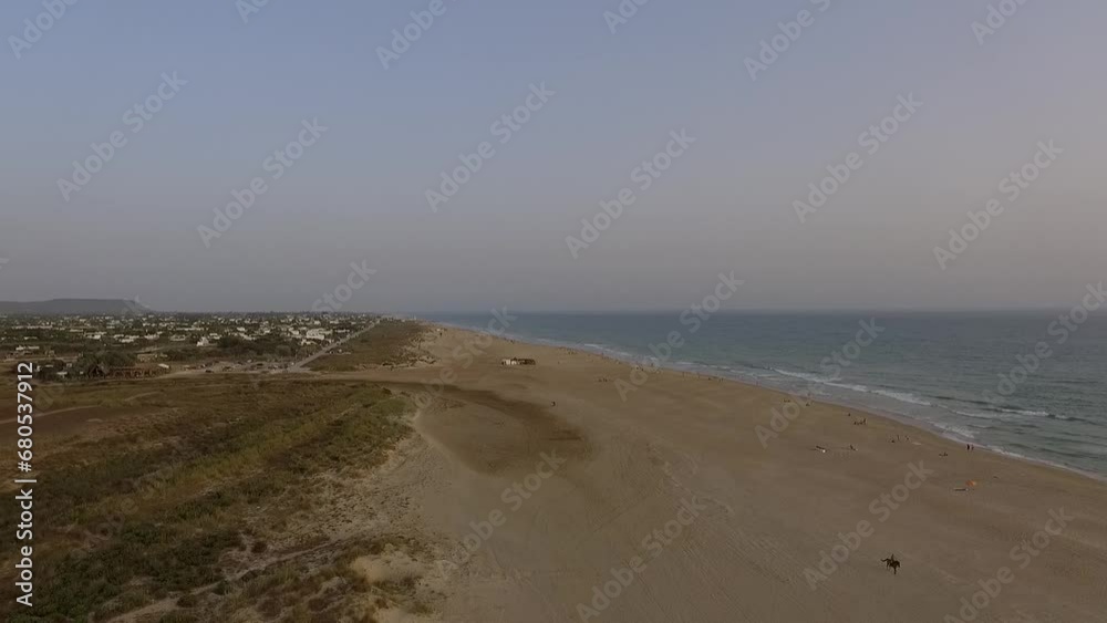 Aerial view of the coast in descending flight and rider on horseback along the beach with view of the town, bathers and sea. Aerial view of the coast in descending flight and rider on horseback along the beach with view of the town, bathers and sea.