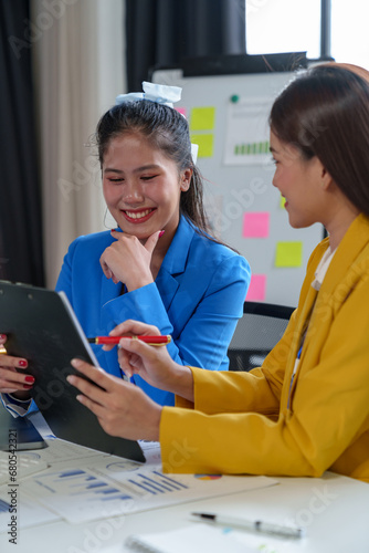 Group of Asian businesswomen talking, consulting, discussing work, presenting new project ideas, analyzing budgets. Report marketing plans and financial investments together within the office.