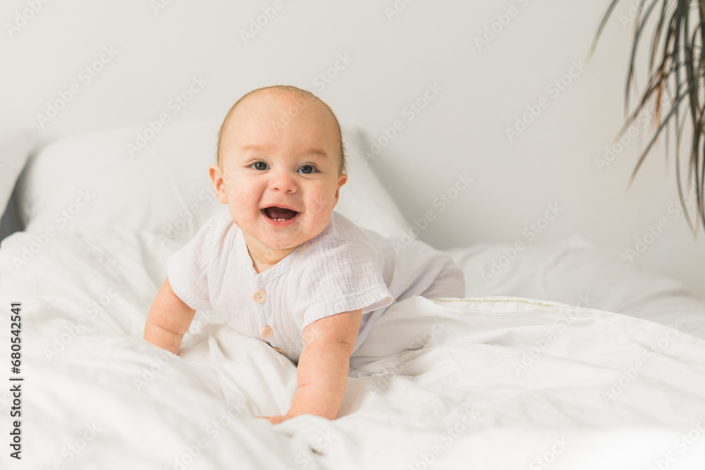Happy baby lying on bed laughing copy space. Generation alpha and gen alpha