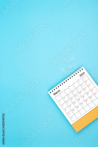 Desk calendar for March 2024 and white paper clip on a light blue background