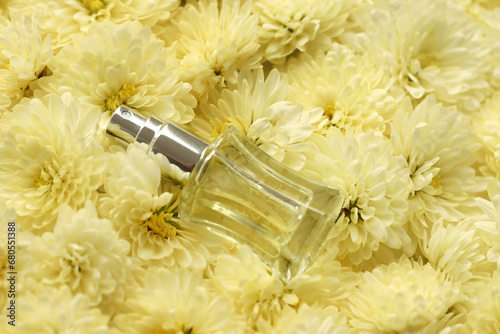 Women fragrance perfume bottle with flowers background close up. Unnamed blank sprayer bottle of perfume for women photo