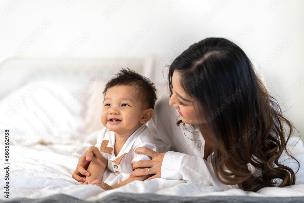 Portrait of enjoy happy love family asian mother playing with adorable little asian baby.Mom touching with cute son moments good time in a white bedroom.Love of family concept Portrait of enjoy happy love family asian mother playing with adorable little asian baby.Mom touching with cute son moments good time in a white bedroom.Love of family concept