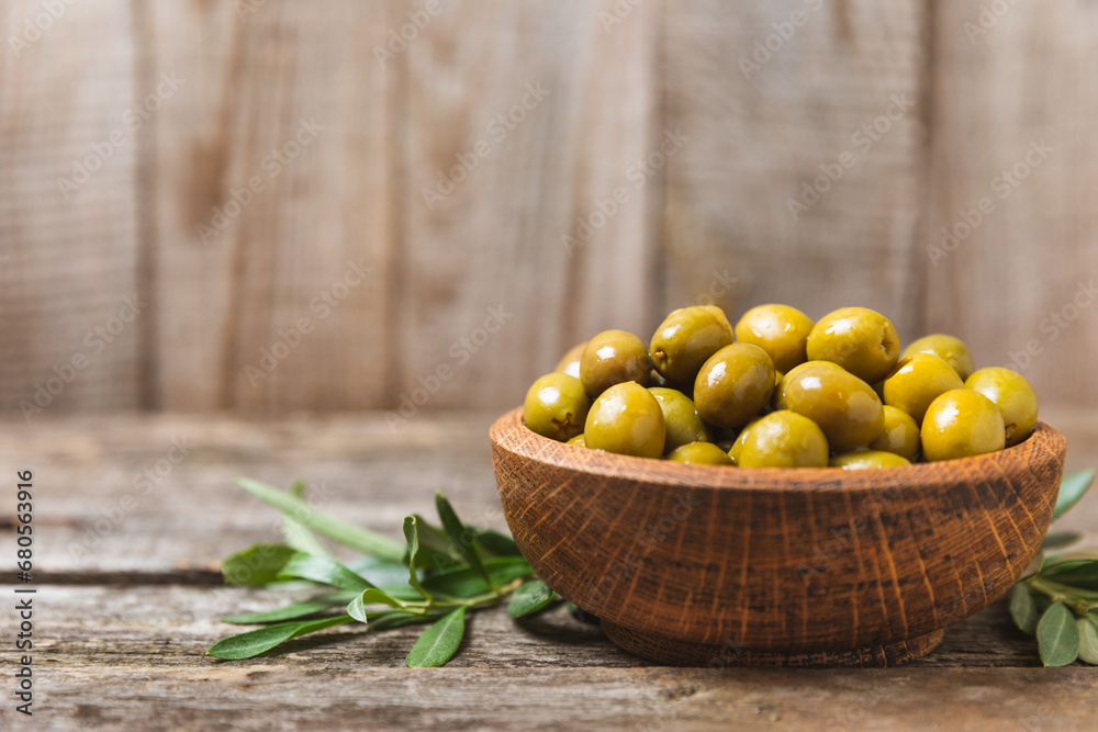 Green olives on a white wooden background. Various types of olives in bowls and olive oil with fresh olive leaves. Copy space. Place for text. Mediterranean food. Vegan. Green olives on a white wooden background. Various types of olives in bowls and olive oil with fresh olive leaves. Copy space. Place for text. Mediterranean food. Vegan.