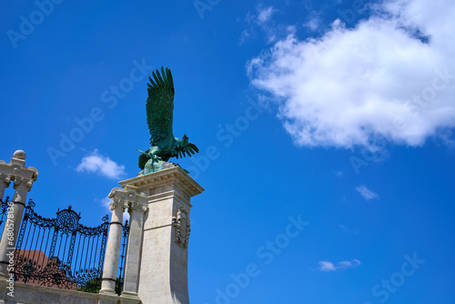 Green copper statue of a large bird with a sword in it's talons and expanded wings on top of a gate near Buda Castle, Budapest, Hungary. photo