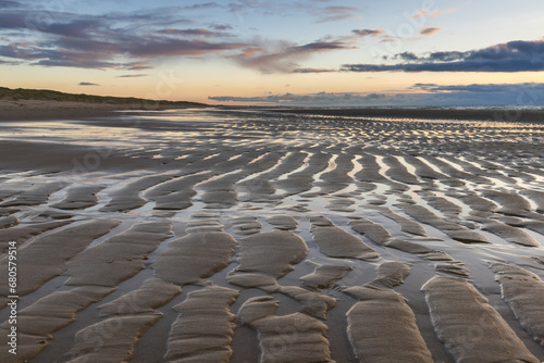 Receding sea leaves ripples on the beach  illuminated by the setting sun. Once the sea has withdrawn  and the transition from high tide to low tide is complete  the coastline retains firm sandy ridges