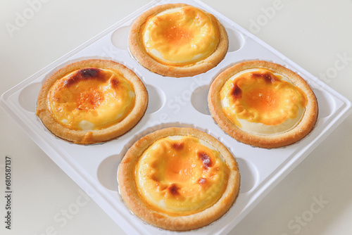 Four delicious golden yellow Chinese custard egg tarts (danta), a popular Chinese baked snack dessert across China, originating from Guangzhou