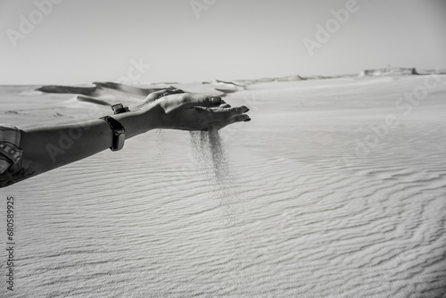 Sand pours out of woman's hands in the desert