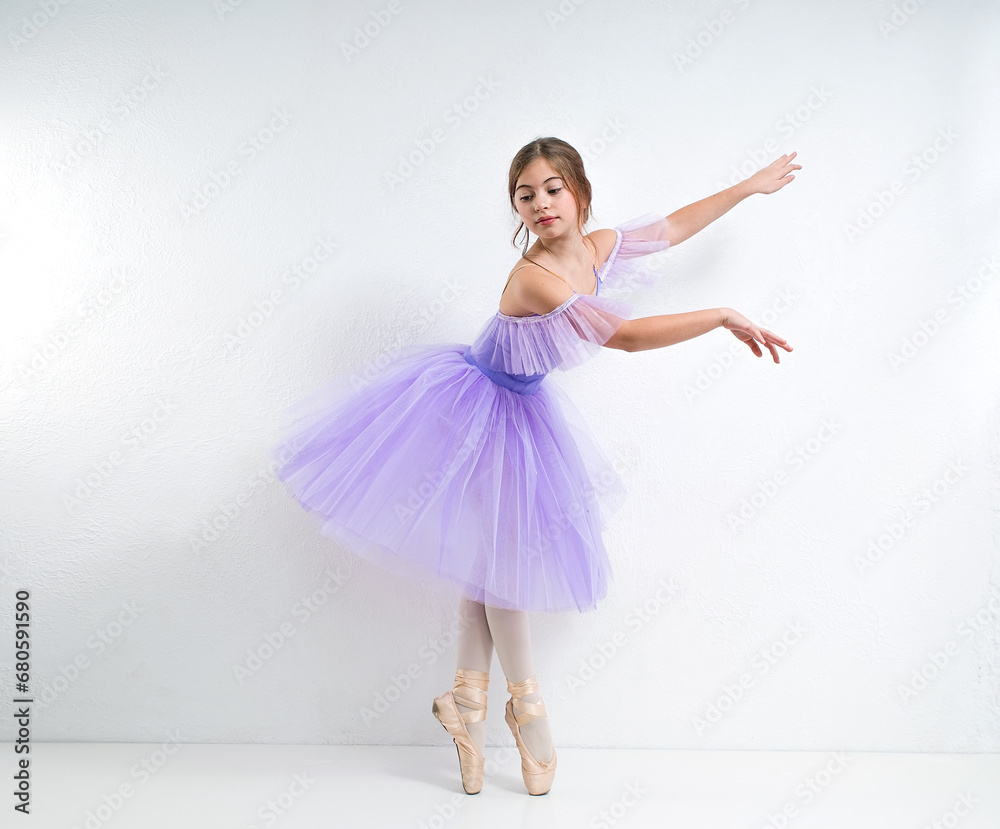 Naklejka premium Young ballerina in a purple dress on a white background.