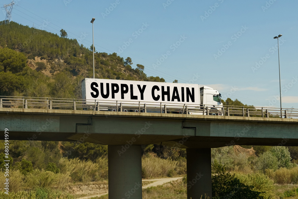 A truck is driving across the bridge, with the inscription on the trailer - SUPPLY CHAIN.