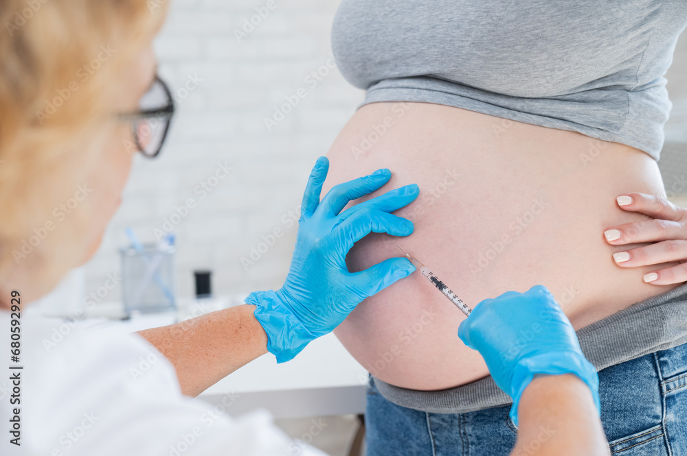 Doctor gives an injection in the stomach of a pregnant woman. 