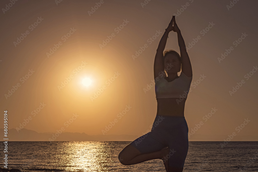Tree yoga pose on the beach at sunrise