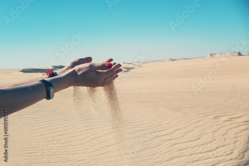 Sand pours out of woman's hands in the desert
