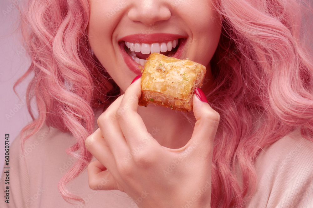 Woman with pink curly hair is eating baklava. Woman with pink curly hair is eating baklava.