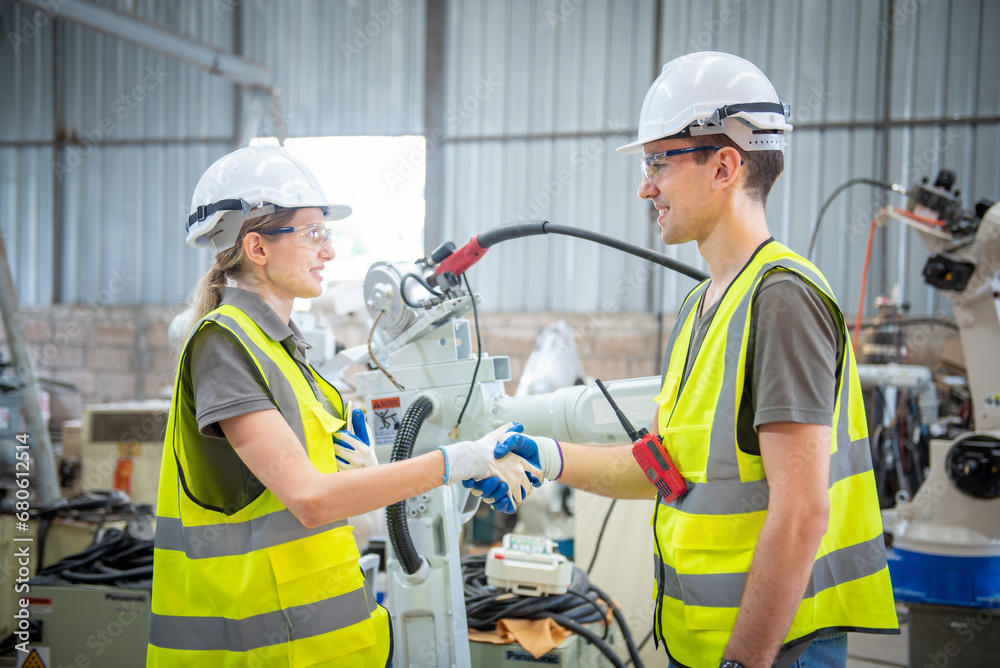 Engineers team mechanic shaking hand in steel factory workshop. Industry robot programming software for automated manufacturing technology Engineers team mechanic shaking hand in steel factory workshop. Industry robot programming software for automated manufacturing technology
