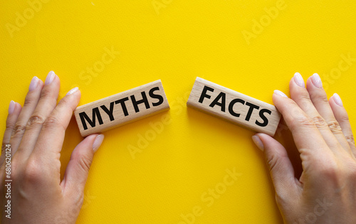 Facts or Myths symbol. Concept word Facts or Myths on wooden blocks. Businessman hand. Beautiful yellow background. Business and Facts or Myths concept. Copy space photo