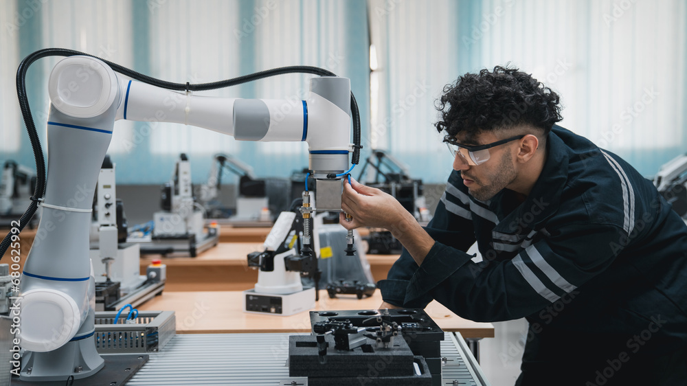 Student engineer Assembling Robotic Arm with computer in Technology Workshop. Service Engineer Holding Robot Controller and Checking Robotic Arm Welding Hardware. Student engineer Assembling Robotic Arm with computer in Technology Workshop. Service Engineer Holding Robot Controller and Checking Robotic Arm Welding Hardware.