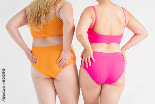 Two overweight women with fat flabby legs, hands, hips and buttocks on gray background, plastic surgery and body positive concept photo
