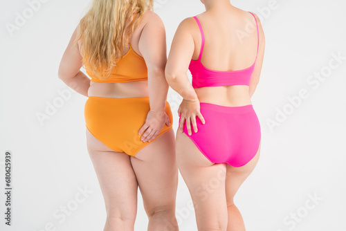 Two overweight women with fat flabby legs, hands, hips and buttocks on gray background, plastic surgery and body positive concept photo