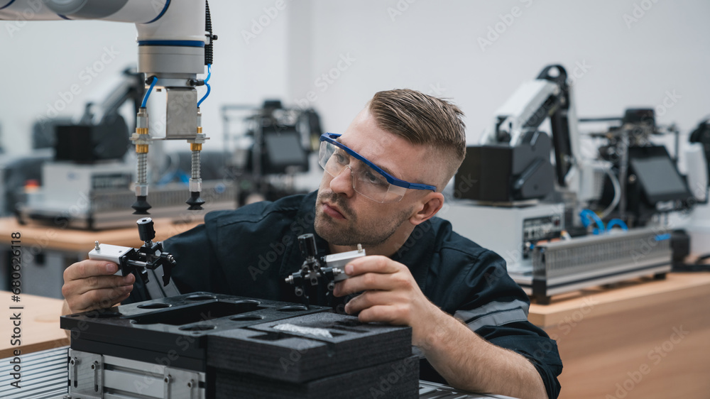 Student engineer Assembling Robotic Arm with computer in Technology Workshop. Service Engineer Holding Robot Controller and Checking Robotic Arm Welding Hardware. Student engineer Assembling Robotic Arm with computer in Technology Workshop. Service Engineer Holding Robot Controller and Checking Robotic Arm Welding Hardware.