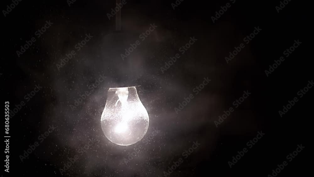 Glowing Light Bulb Illuminates the Falling Snow in a Thick Fog in the Dark. Black background. Blizzard, snowfall. Street lamp. Christmas background. Warm light. Texture. Isolated. Flying particles. Glowing Light Bulb Illuminates the Falling Snow in a Thick Fog in the Dark. Black background. Blizzard, snowfall. Street lamp. Christmas background. Warm light. Texture. Isolated. Flying particles.