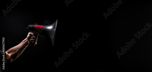 single hand holds a megaphone against a pitch black background photo