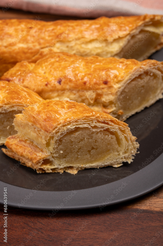 Fresh baked Dutch filled spicy cookies from puff pastry with almonds on black board close up Fresh baked Dutch filled spicy cookies from puff pastry with almonds on black board close up