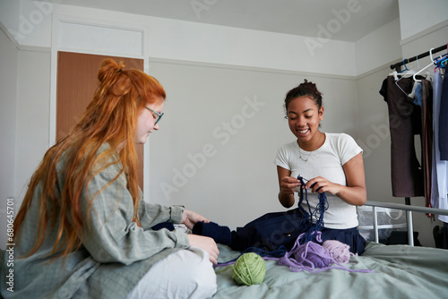 Gen Z girl smiling as she works on knitted pieces alongside her friend. Concept of gender-neutral and sustainable fashion and self expression