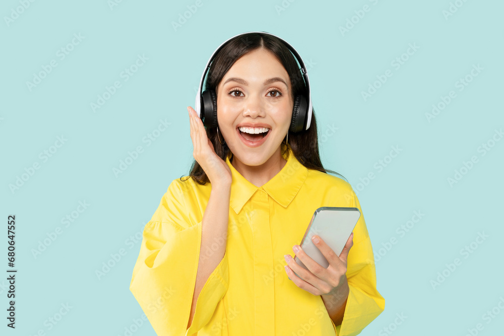 Excited young woman enjoying music, using headphones and smartphone Excited young woman enjoying music, using headphones and smartphone