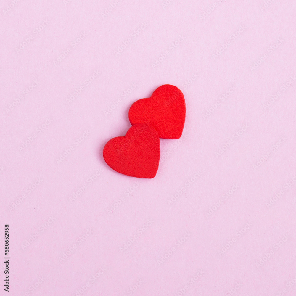 Background for Valentine's day. Two red hearts on the pink background. Top view. Close-up.